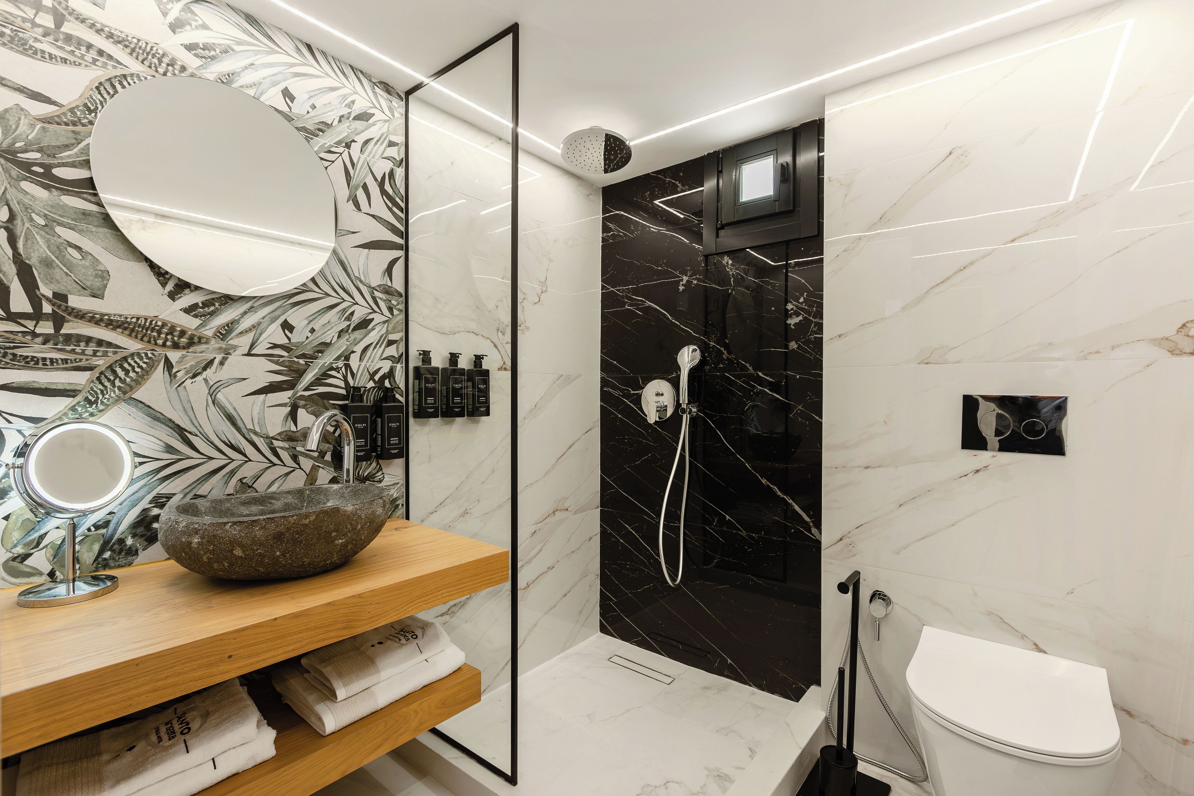 Un baño moderno con lavamanos de piedra, un espejo, ducha y retrete.