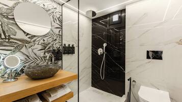 Un baño moderno con lavamanos de piedra, un espejo, ducha y retrete.