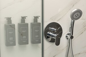 Un baño con tres botellas de ducha con la etiqueta 'CULTI' y un cabezal de ducha moderno.