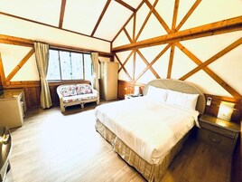 Un dormitorio con una cama grande, techo de madera, ventana con cortinas, mesita de noche y tocador.