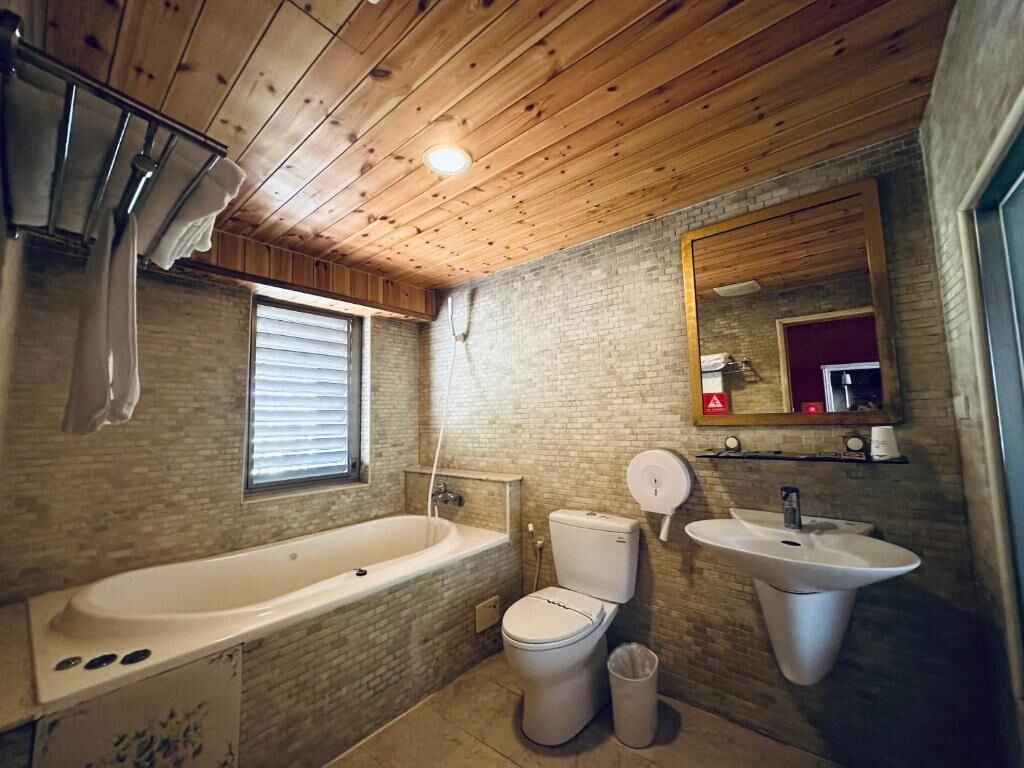 Ein Badezimmer mit Holzboden, einer Badewanne, einer Toilette, einem Waschbecken und einem Spiegel.