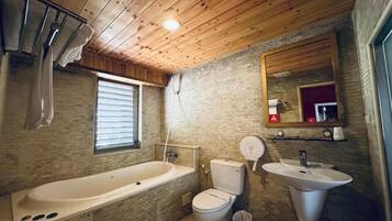 Ein Badezimmer mit Holzboden, einer Badewanne, einer Toilette, einem Waschbecken und einem Spiegel.