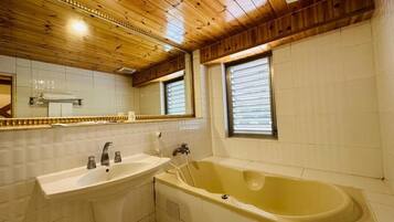 A bathroom with a wooden ceiling, a sink, a bathtub, and a window with blinds.