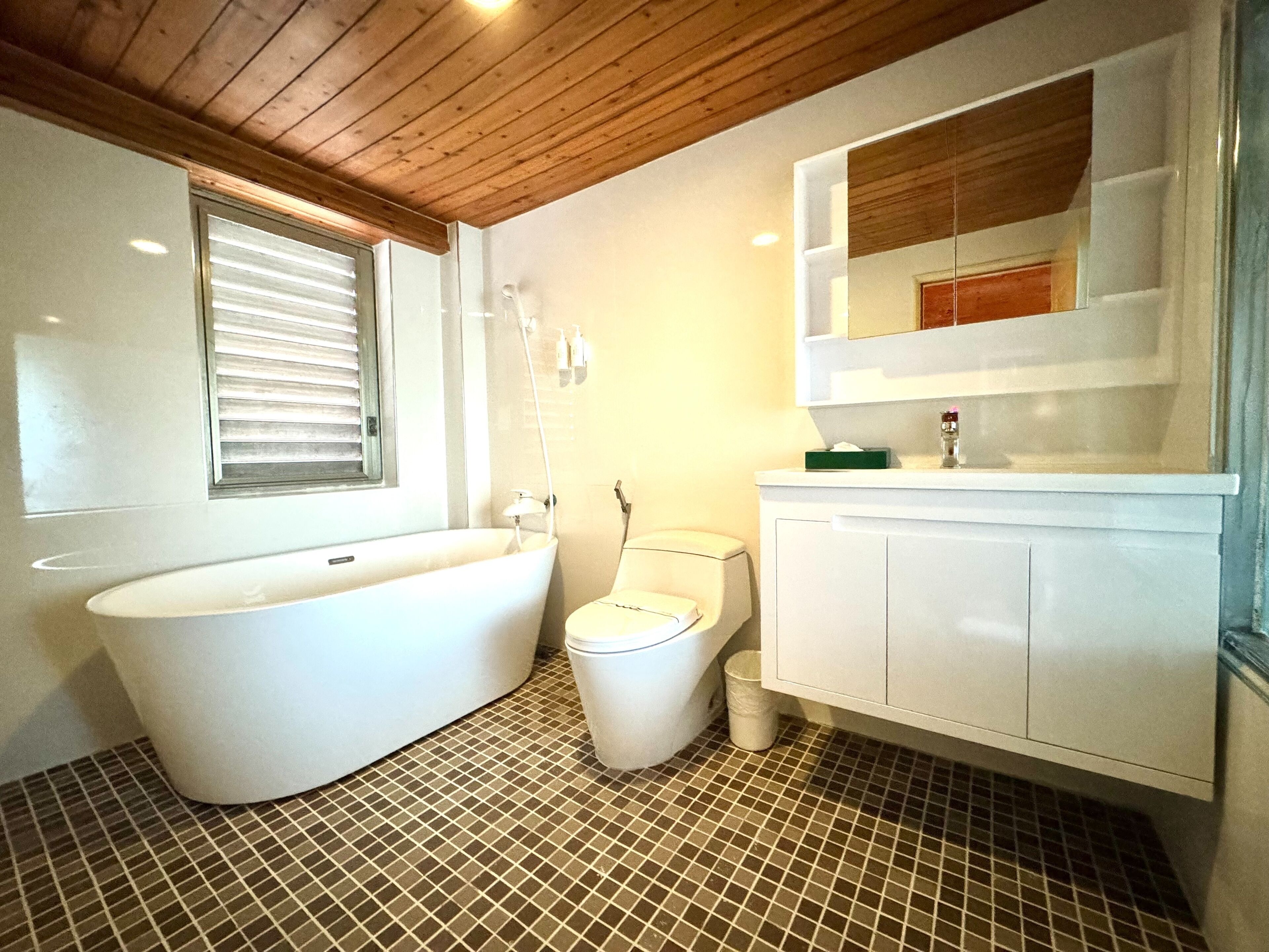 Un baño con bañera independiente, inodoro y tocador con espejo.
