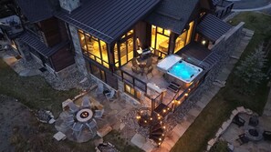 A modern house with a hot tub, outdoor seating, and a fire pit.