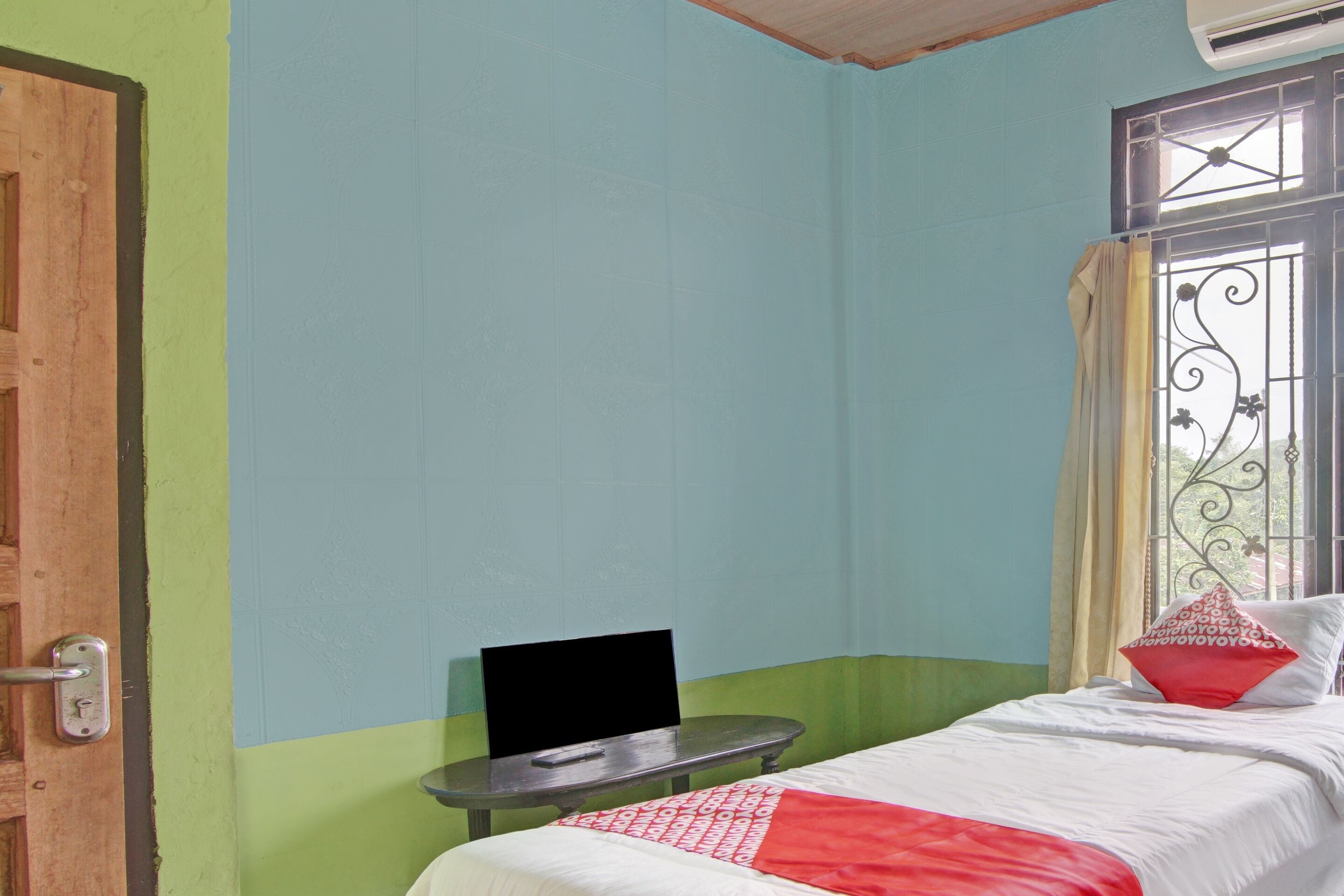 A room with a bed, a small table, and a window with metal bars.