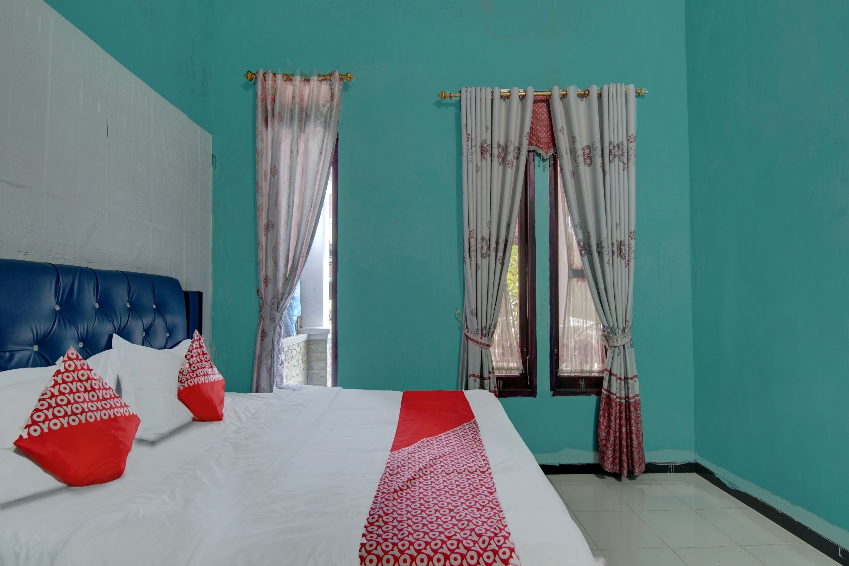 Une chambre avec un lit, des murs de couleur turquoise et des rideaux.