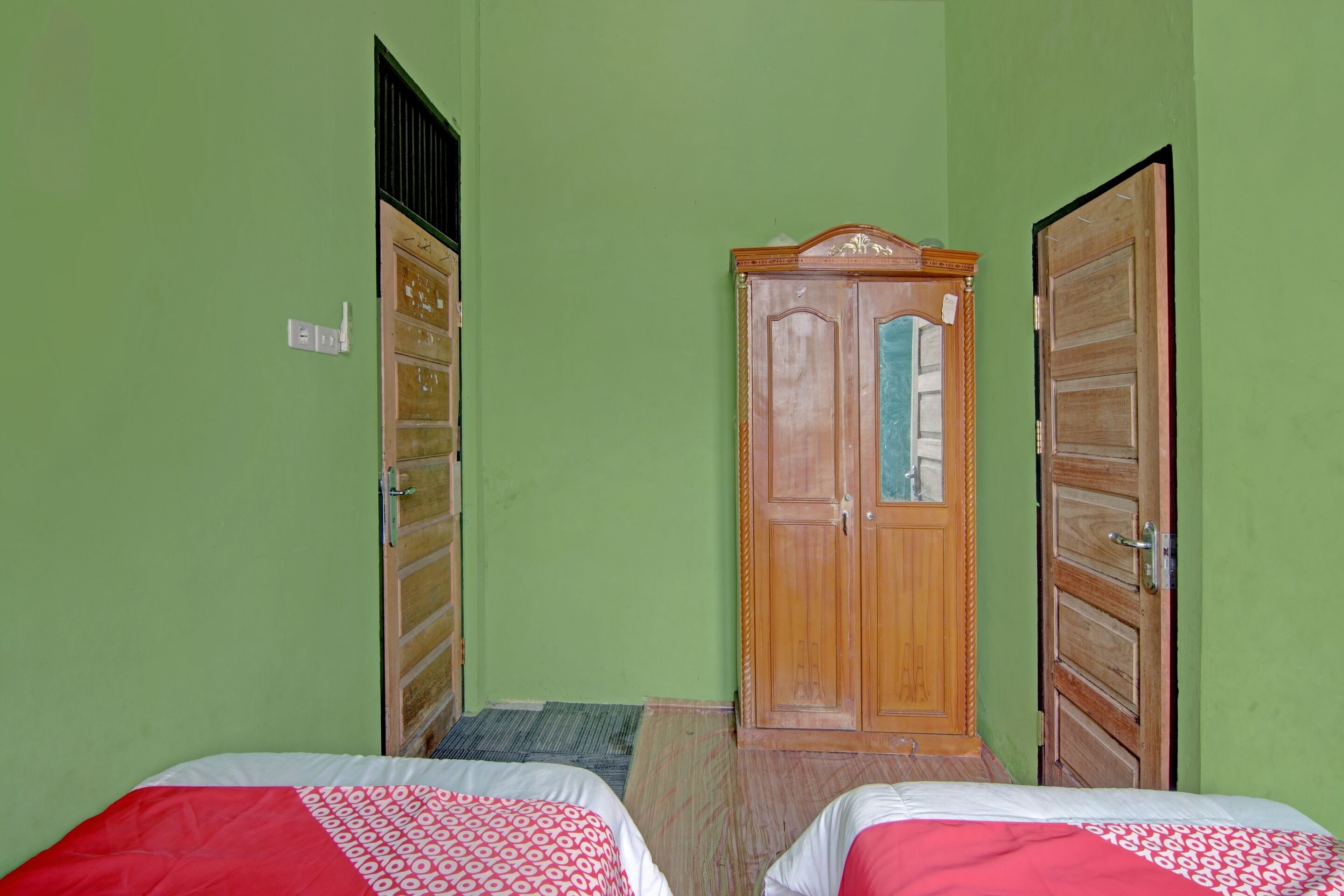 Una habitación con dos camas, un armario de madera y una puerta con espejo.