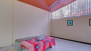 Een kamer met een betegelde vloer, een tafel met een laptop en een rode tafelkleed.