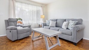 Een woonkamer met een grijze bank, een grijze fauteuil en een houten salontafel.