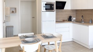 Una cocina moderna con armarios blancos, microondas integrado y un lavabo.