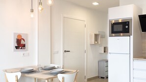 Una cocina moderna con microondas y horno integrados, una mesa de comedor con sillas y una puerta que da a otra habitación.