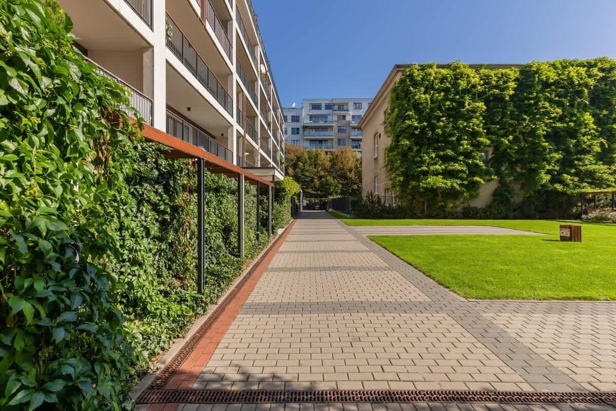 Een pad dat leidt naar een modern gebouw met een bakstenen gevel en een groen gazon.