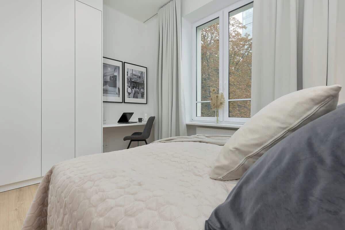 Ein Schlafzimmer mit einem Bett, einem Schreibtisch und einem fensterbepflanzten Fenster.