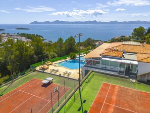 Une propriété résidentielle dotée d’une piscine, de courts de tennis et offrant une vue sur la mer.