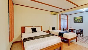 Ein Hotelzimmer mit zwei Betten, einer Holzbalkendecke, einer Klimaanlage, einem kleinen Tisch und einem Stuhl.