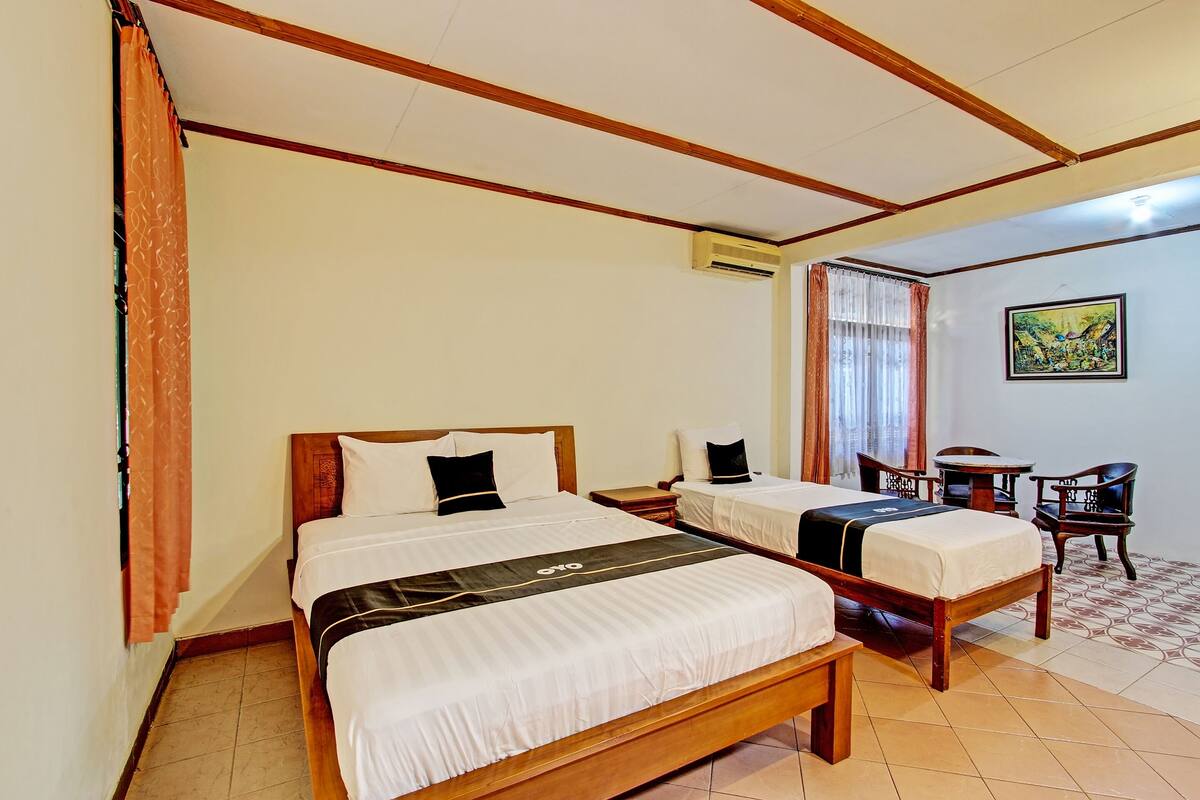 Une chambre d’hôtel avec deux lits, un plafond en bois, un appareil de climatisation, une petite table et une chaise.