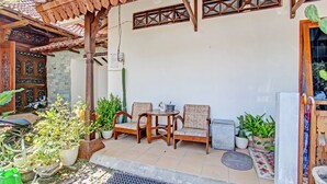 Ein überdachter Patio-Bereich mit Holzmöbeln, Topfpflanzen und einem kleinen Tisch.