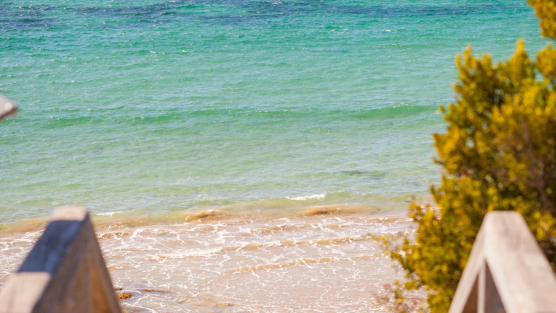 A beach with clear water and wooden structures.
