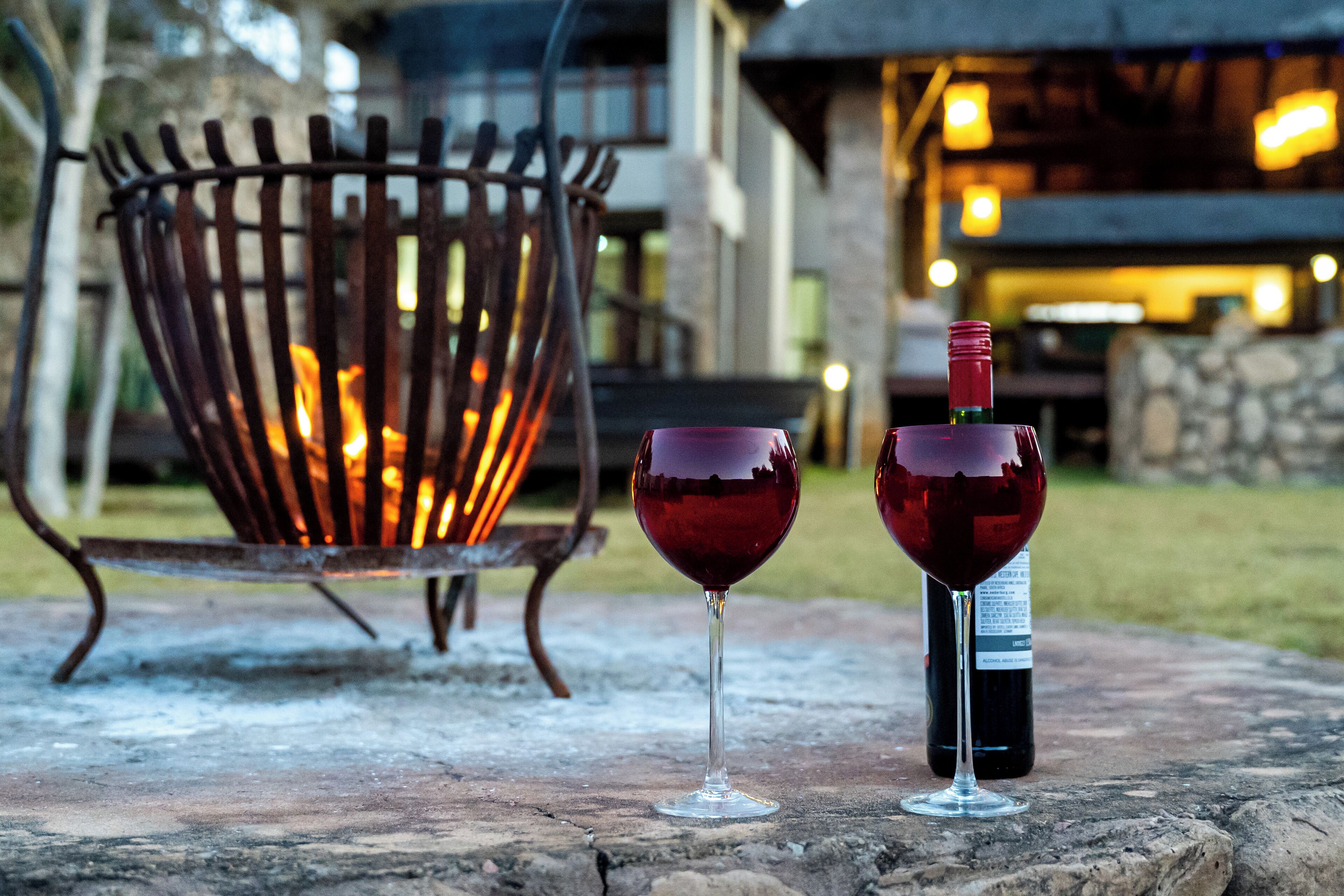 A stone patio with two wine glasses and a bottle of wine.