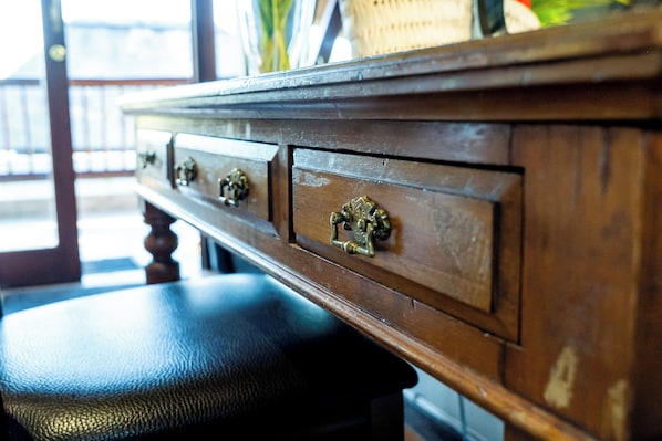 A wooden dresser with brass handles and a black leather bench.