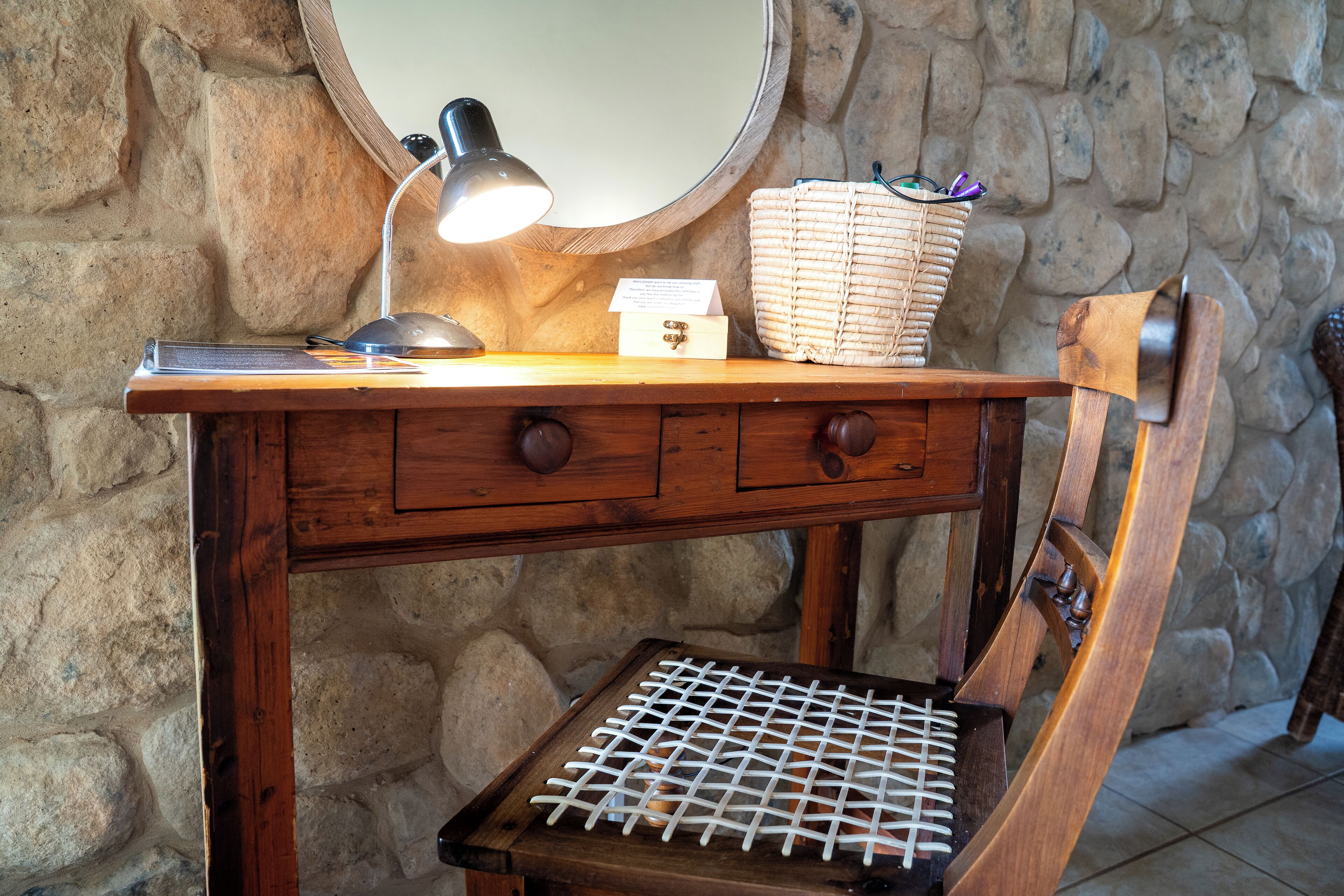 A wooden desk with a lamp, a wicker basket, and a small box.
