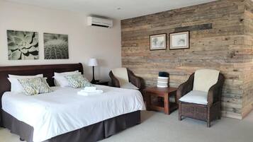 A hotel room with a large bed, two armchairs, a small table, and artwork on the walls.