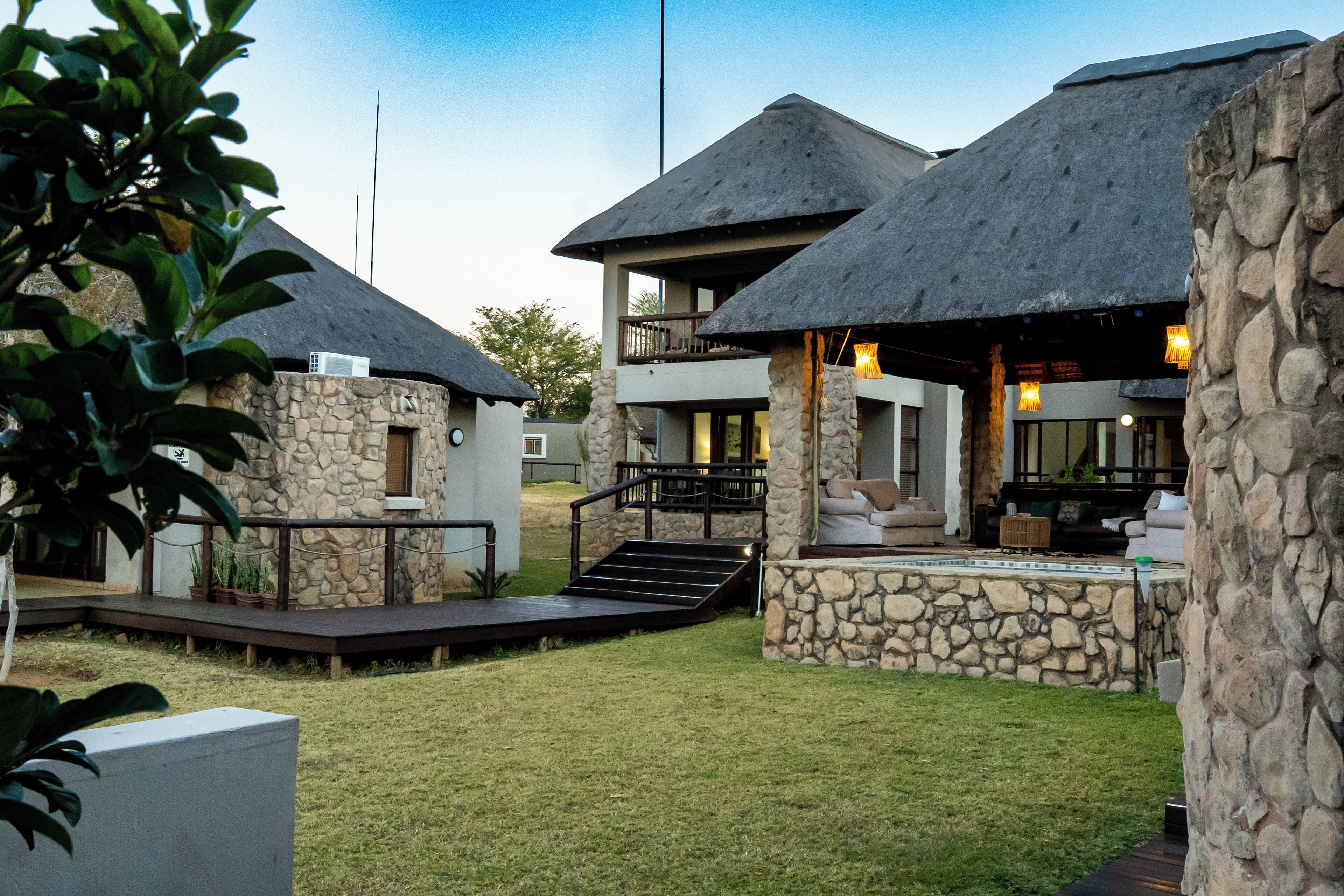 A resort with thatched-roof cottages, stone walls, and a well-maintained lawn.