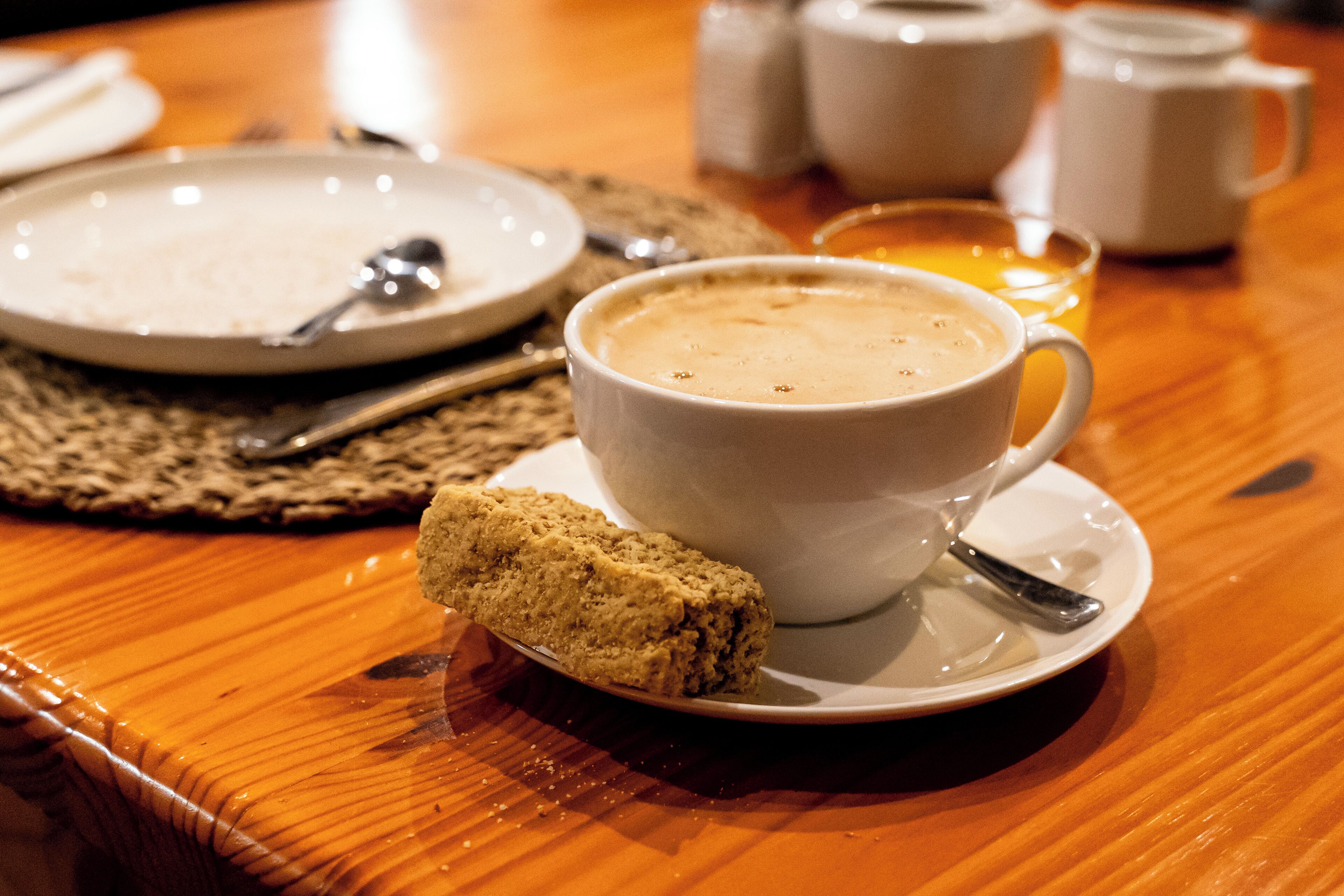 Una taza de café con una galleta sobre una mesa de madera.
