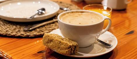 Une tasse de café et un biscuit sur une table en bois.
