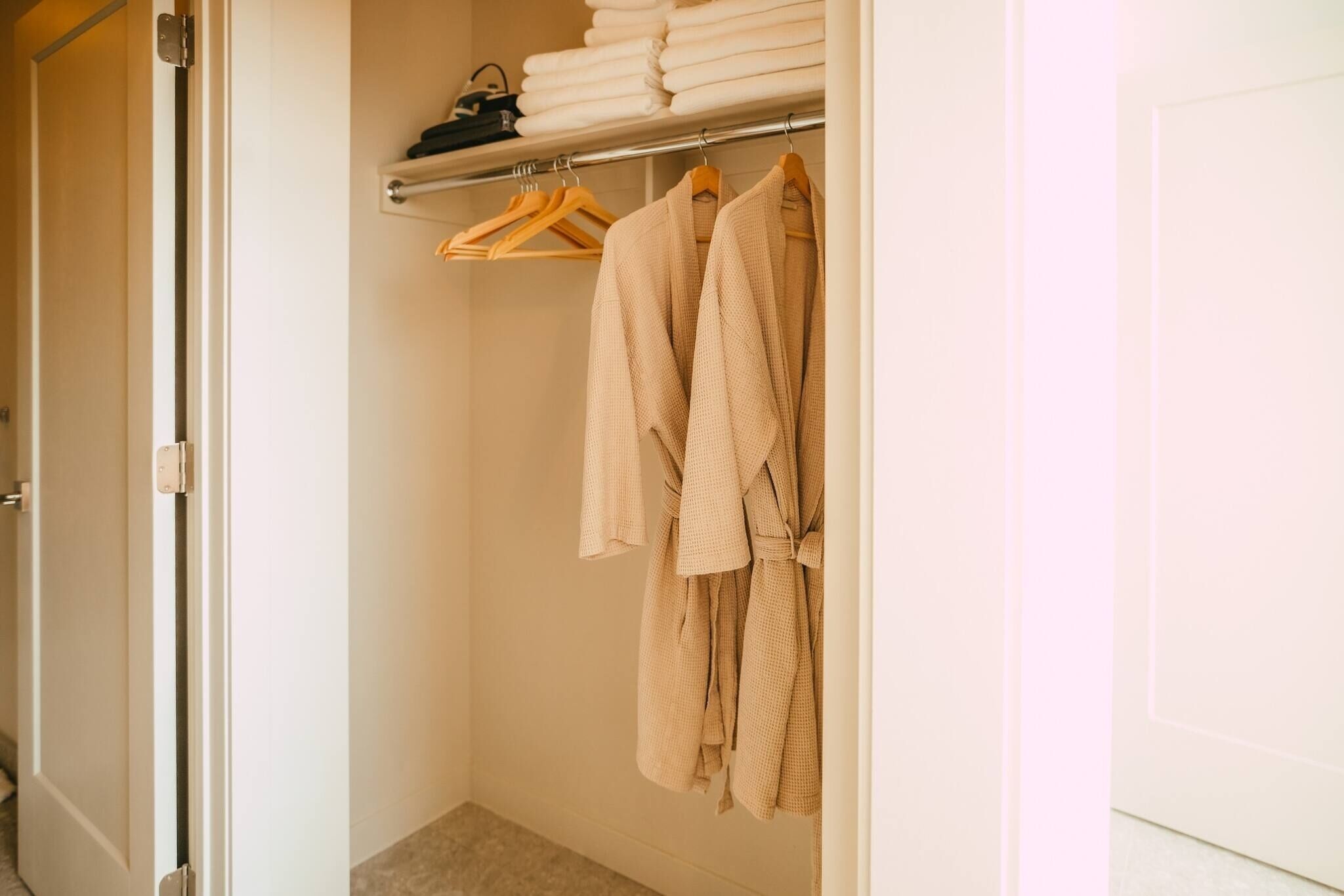A walk-in closet with a hanging rack holding folded towels and robes.