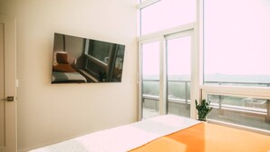 Un dormitorio con cama, ventana, cuadro y balcón.
