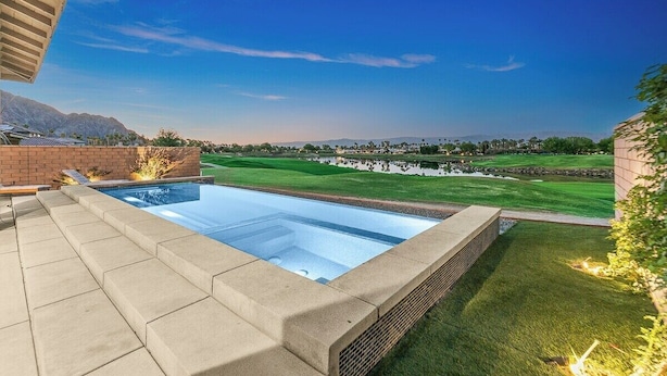 Una piscina con vistas a un campo de golf y montañas.