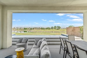 Un espacio al aire libre moderno con mobiliario y vistas a un campo de golf y una masa de agua.