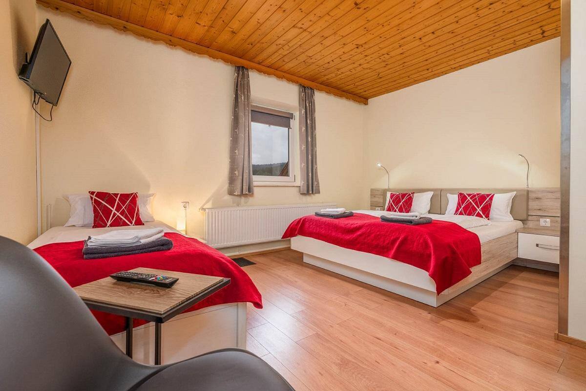 Une chambre d’hôtel avec deux lits, une télévision, une fenêtre et une table.