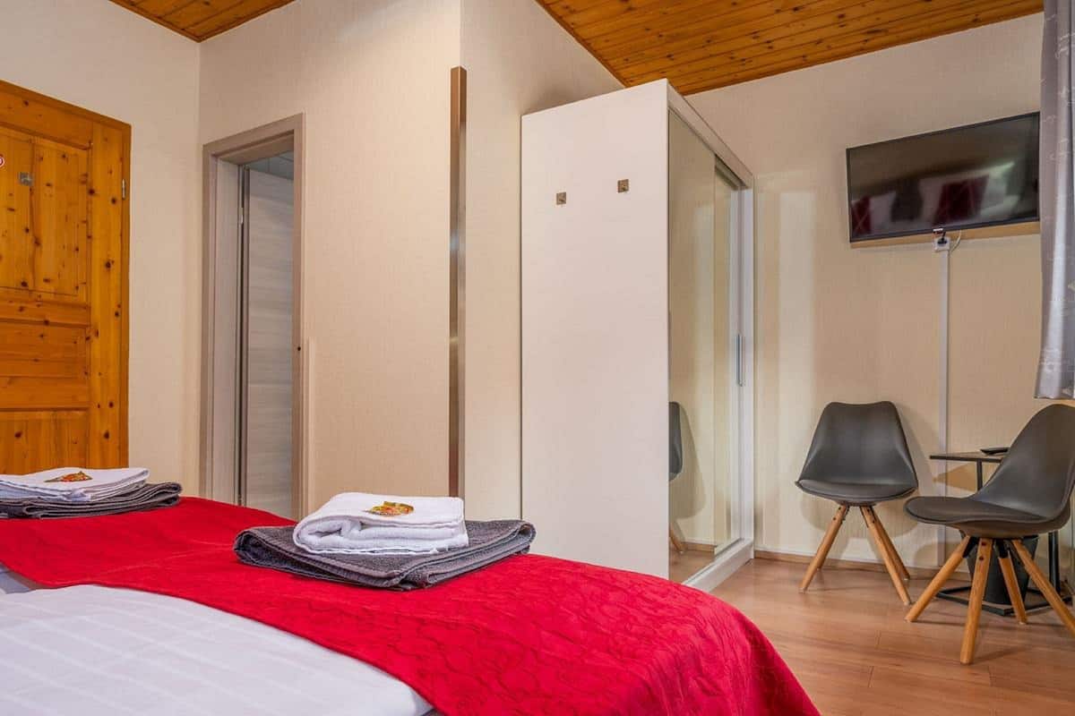 Une chambre d’hôtel avec un lit, une télévision, une porte en bois et un miroir.