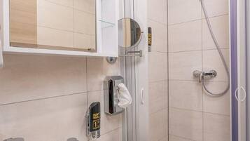 A modern bathroom with a white sink, a mirror, and a shower enclosure.