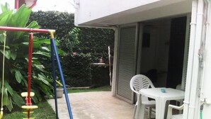 A patio area with a swing set, a table with chairs, and a potted plant. - Quartier Calme, Centre Ville, gde Chambre Piscine.................; (noumea)