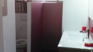 A small, compact bathroom with a toilet, a sink, and a window providing natural light. - Quartier Calme, Centre Ville, gde Chambre Piscine.................; (noumea)