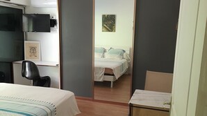 A bedroom with a bed, a desk, a chair, a wardrobe, and a mirror. - Quartier Calme, Centre Ville, gde Chambre Piscine.................; (noumea)