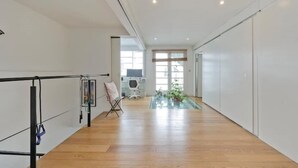 A spacious hallway with wooden flooring, a ballet barre, and a folding chair. - Loft Style Apartment (London)