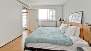 A bedroom with a bed, a wooden headboard, a window, and a door leading to another room. - Loft Style Apartment (London)