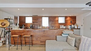 A modern kitchen with a wooden countertop, bar stools, and a built-in oven. - Loft Style Apartment (London)
