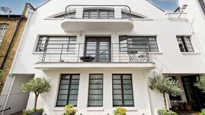 A two-story building with a balcony, large windows, and a satellite dish. - Loft Style Apartment (London)