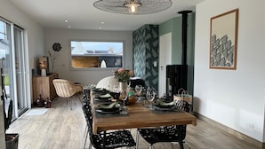 A dining area with a wooden table set for four, surrounded by black chairs, a pendant light, and a view of the outdoors. - Villa Ty Plad, Penmarc'h (Penmarc'h)