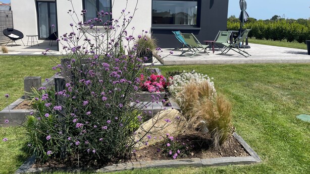 A modern house with a patio area featuring outdoor furniture and a garden with various plants and flowers. - Villa Ty Plad, Penmarc'h (Penmarc'h)