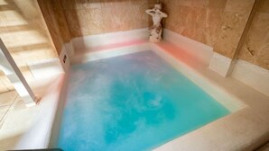 A spa pool with a gradient of blue and pink water, a statue, and a tiled floor. - Spa Retreat (relaxation centre) (Portsmouth)