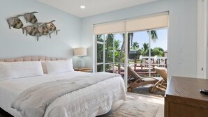 A bedroom with a large bed, a ceiling fan, a nightstand, a lamp, and a view of the outdoors through a sliding glass door. - Waterfront 3BR/3BA Marco Island home with heated pool and free WiFi. (Marco Island)