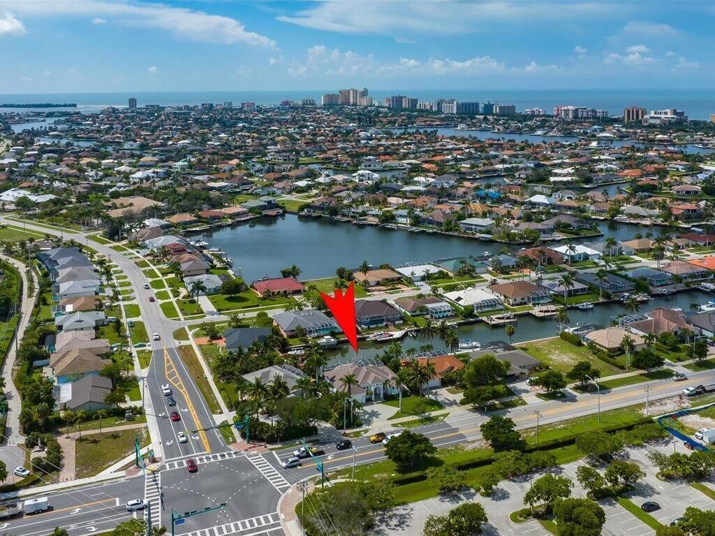 An aerial view of a coastal residential area with a marina, roads, and buildings.