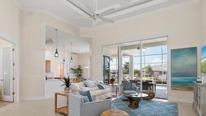 A spacious living room with a sofa, coffee table, and a large window offering a view of the outdoors. - Waterfront 3BR/3BA Marco Island home with heated pool and free WiFi. (Marco Island)